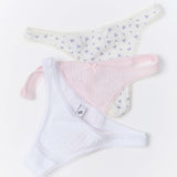 Three pairs of women's underwear laid flat on a white background: a white pair with a small blue floral print, a light pink pair with a tiny bow, and a white pair.