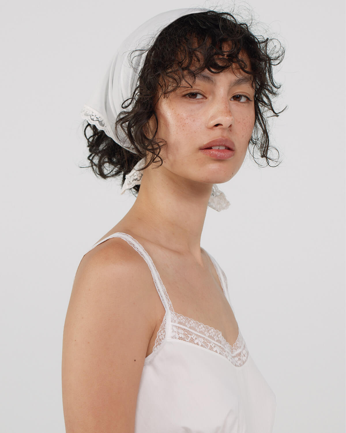 Woman wearing a white lace scarf with a plain background