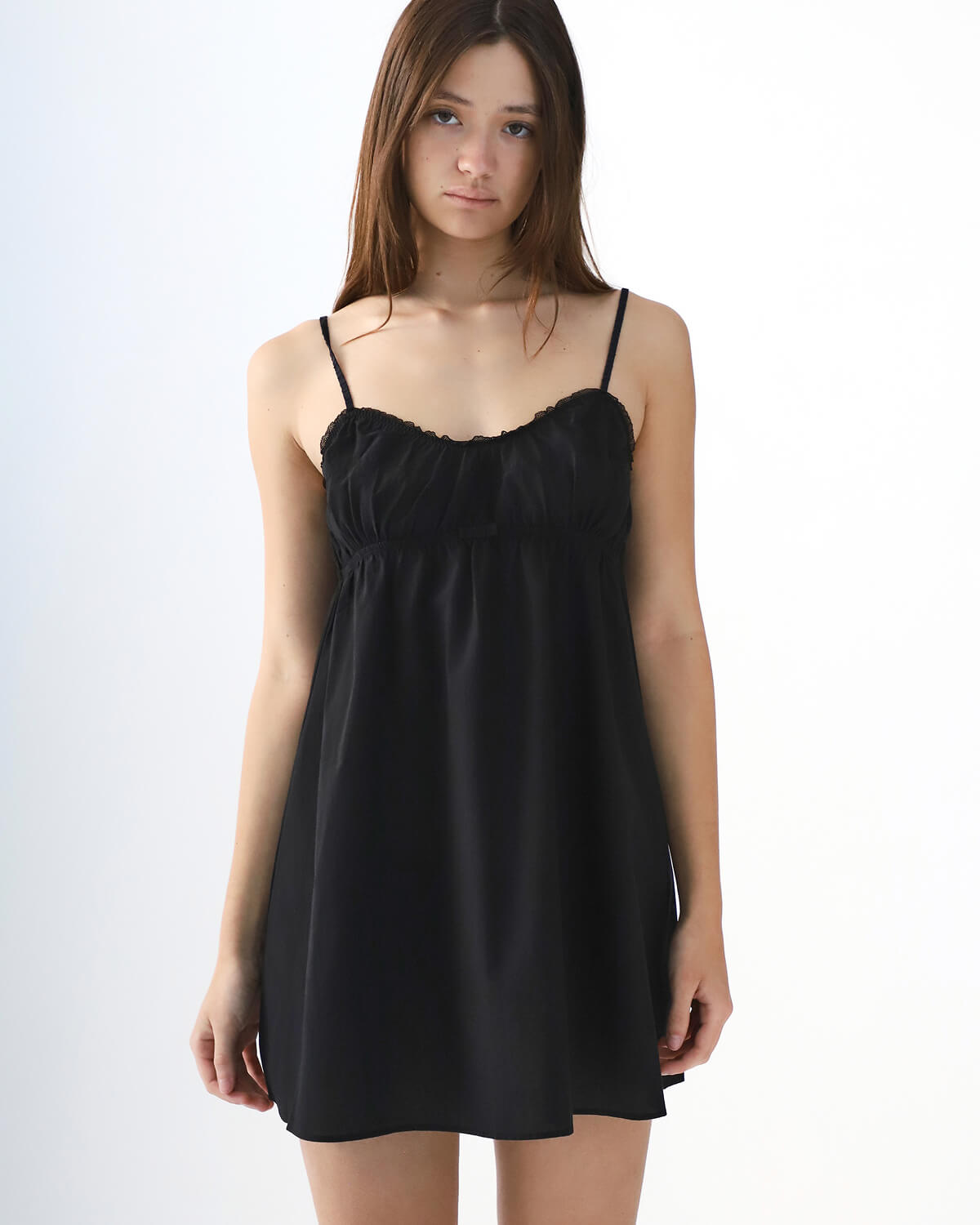 Woman wearing a black slip dress against a white background