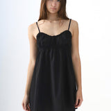Woman wearing a black slip dress against a white background