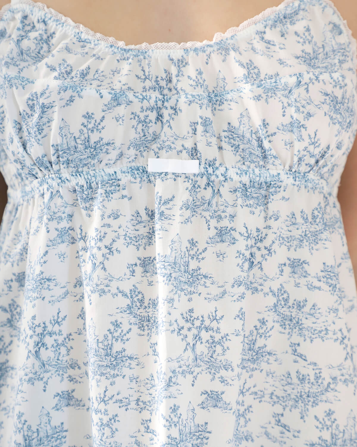 White dress with blue floral pattern on a plain background