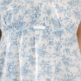 White dress with blue floral pattern on a plain background