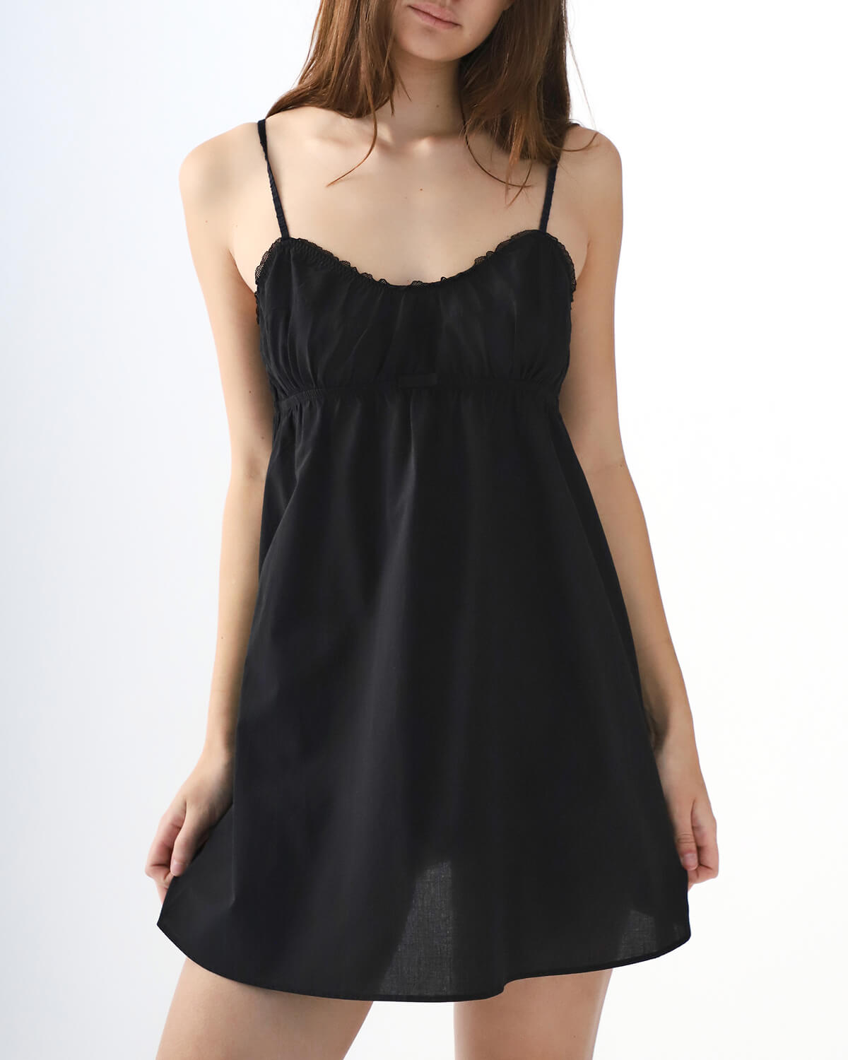 Black slip dress worn by a model on a white background