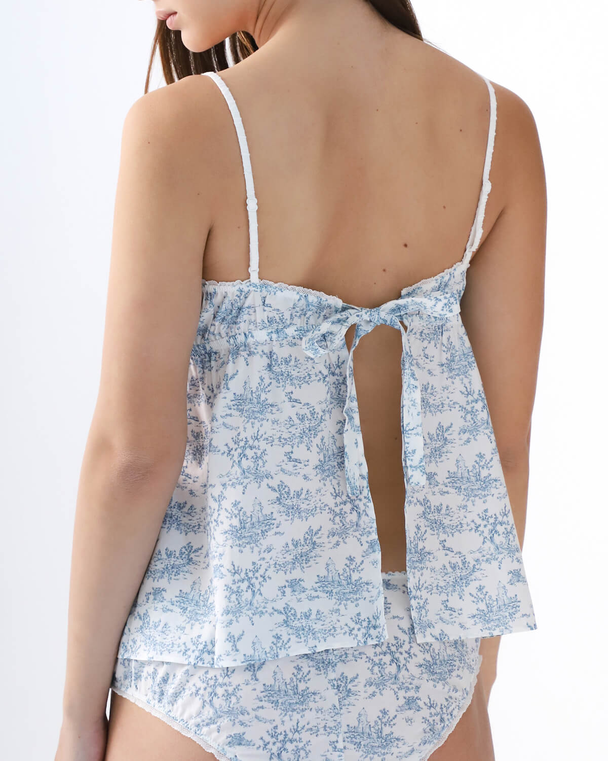 Woman wearing a blue floral tank top with thin straps on a white background