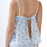 Woman wearing a blue floral tank top with thin straps on a white background