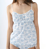 Woman wearing a blue floral camisole and high-waisted underwear on a white background