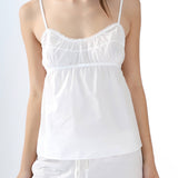 White spaghetti strap top worn by a person on a plain background