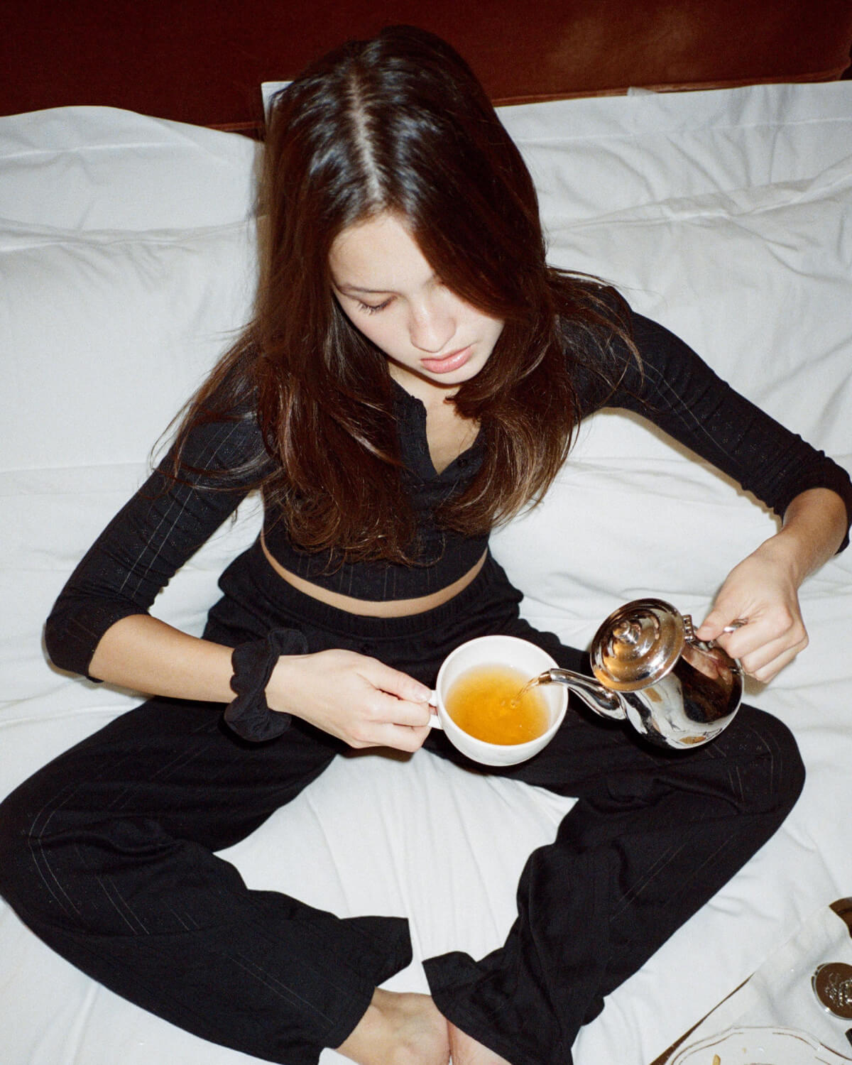 Woman pouring tea into a cup on a bed