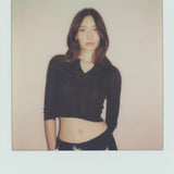 Polaroid-style photo of a person wearing a black jacket with a beige background