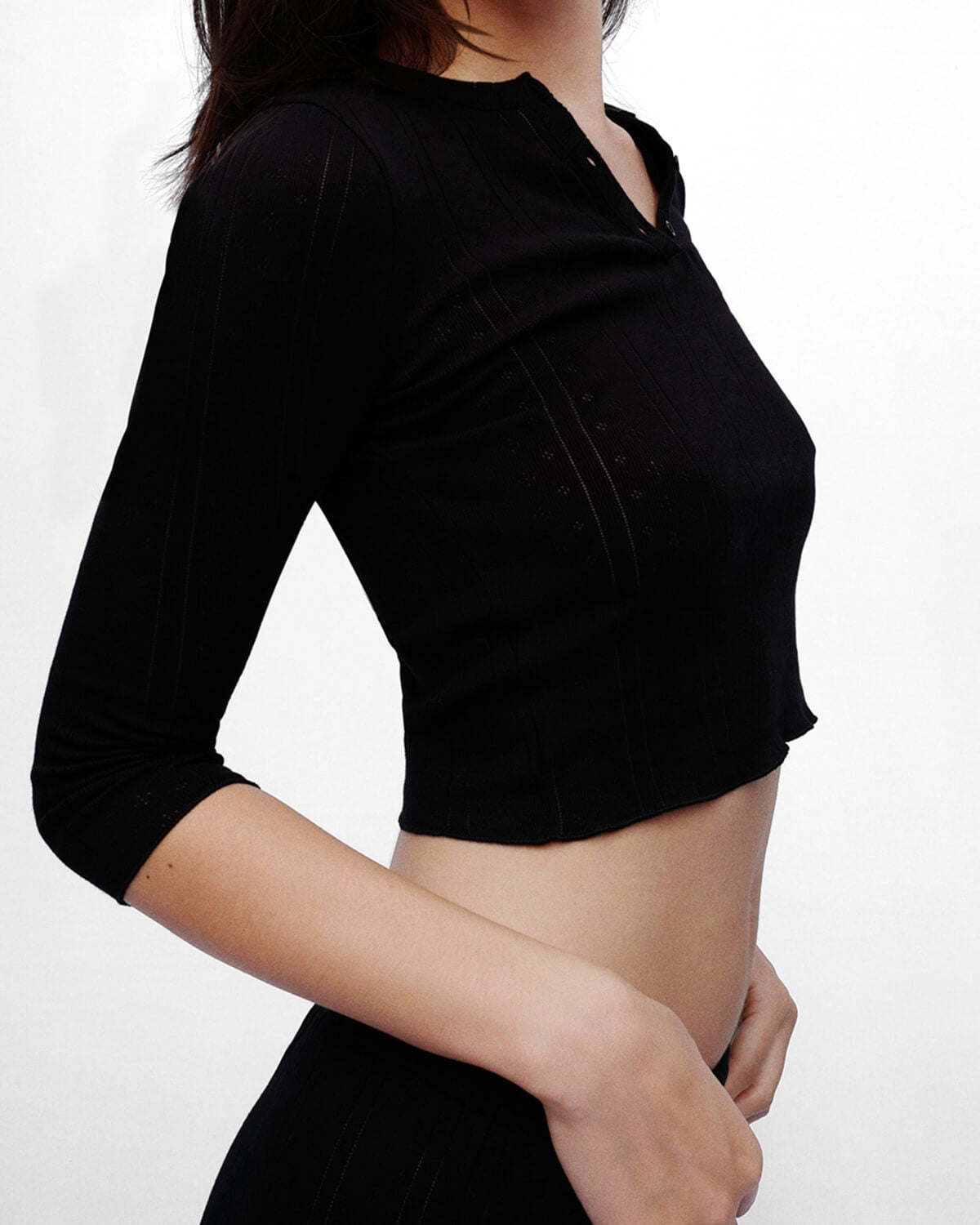 Black crop top worn by a person on a white background