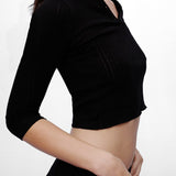 Black crop top worn by a person on a white background