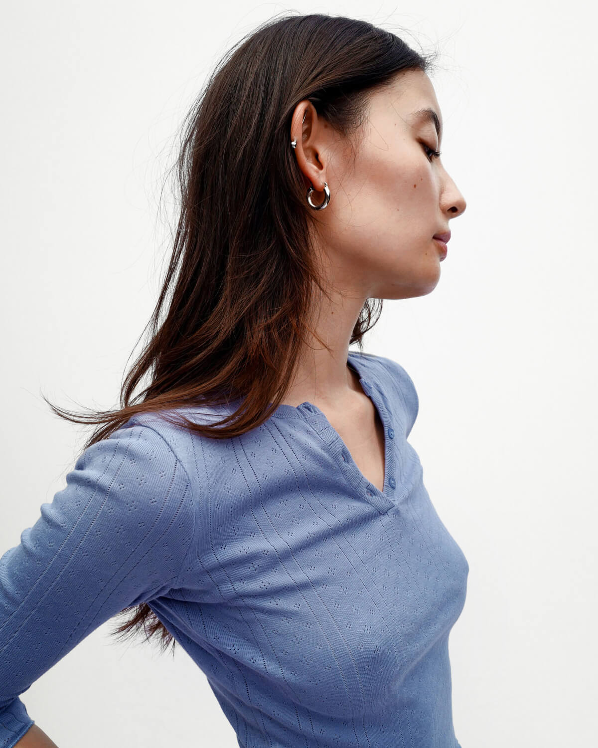 Woman wearing a blue long-sleeve top against a white background
