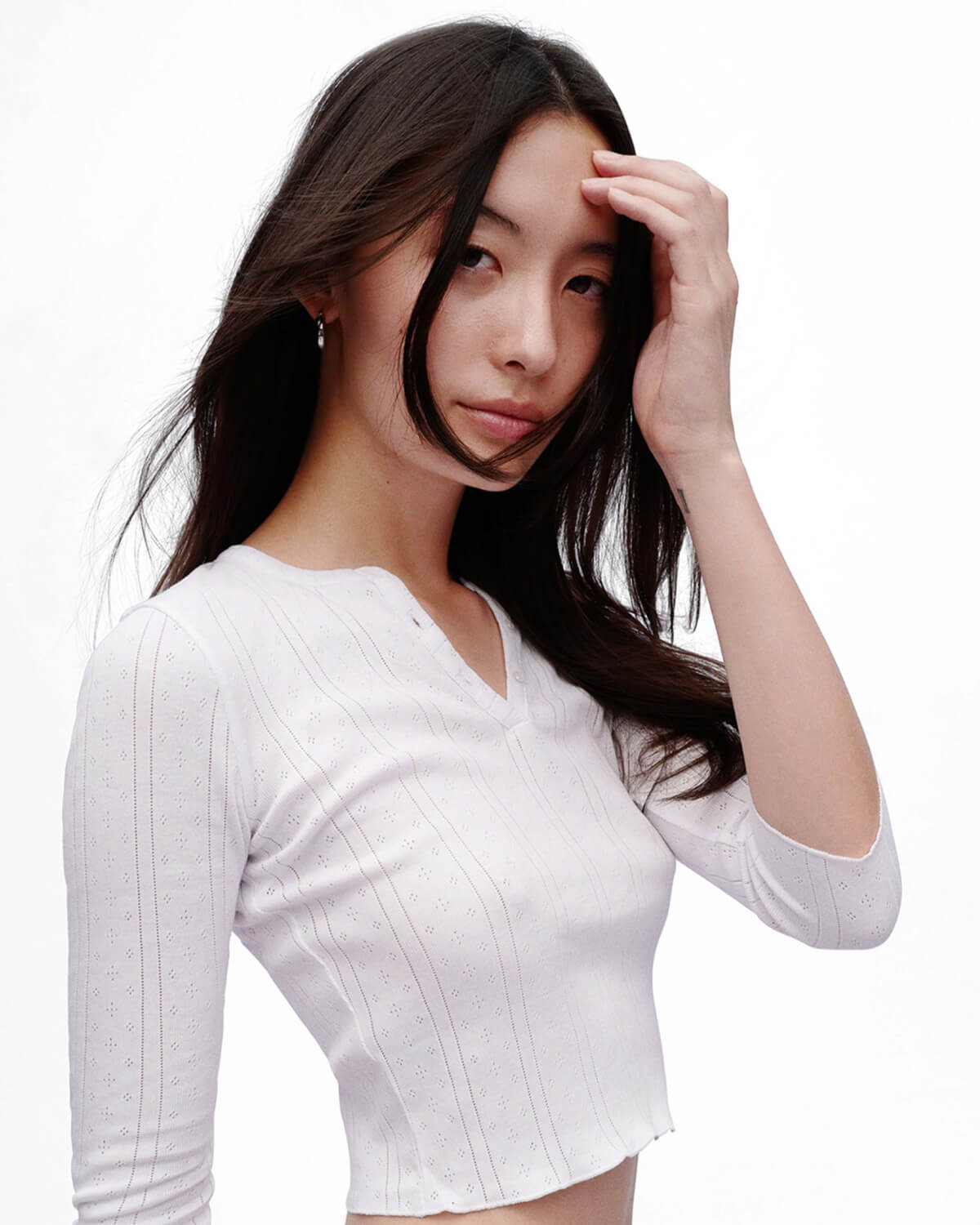Woman wearing a white ribbed sweater against a plain background