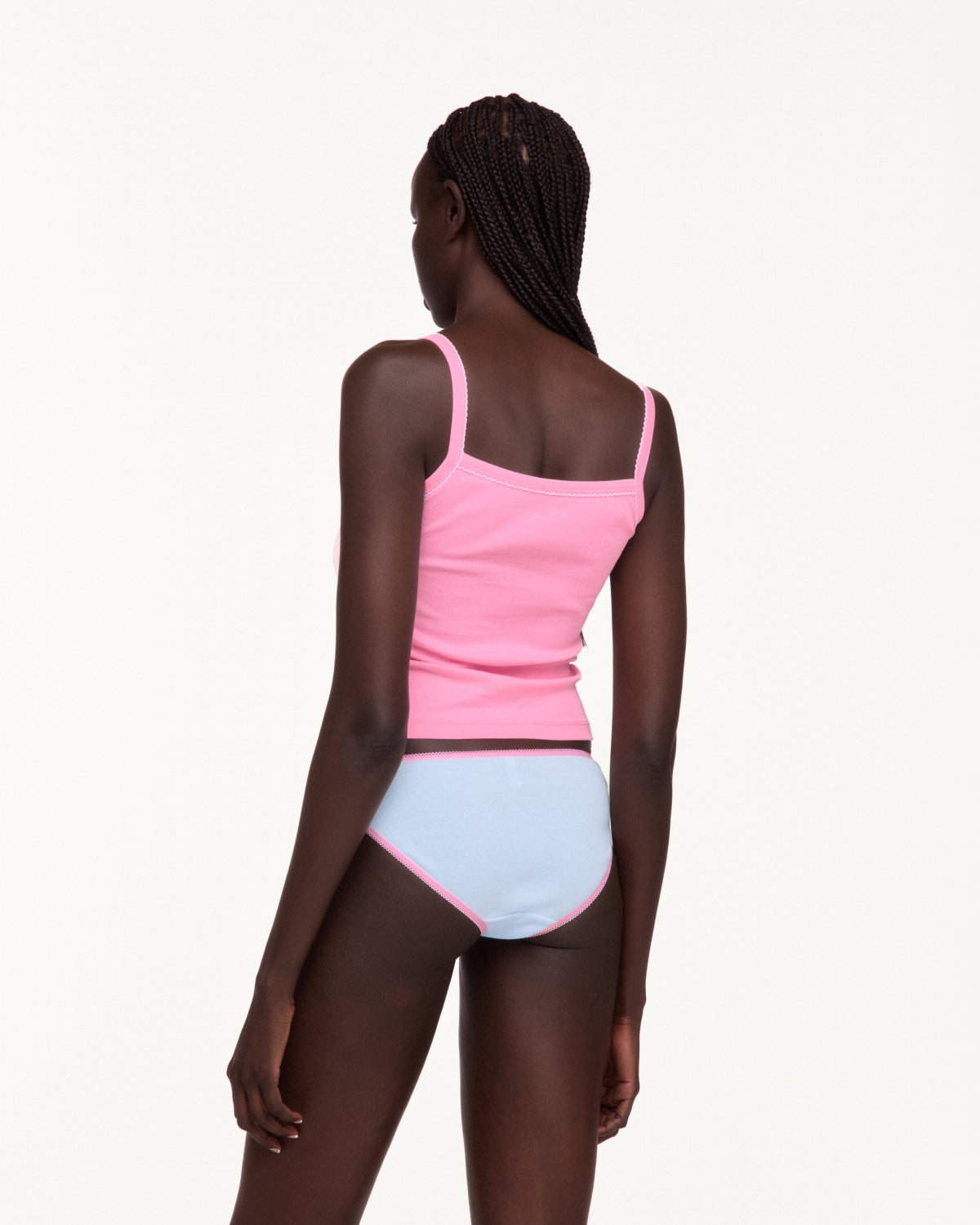A model shown from the back wearing a bright pink ribbed tank top and light blue ribbed underwear with pink trim, against a plain off-white background.