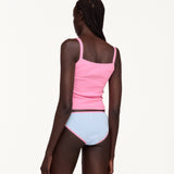 A model shown from the back wearing a bright pink ribbed tank top and light blue ribbed underwear with pink trim, against a plain off-white background.