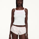 A model wearing a white camisole top and matching white shorts with pink patterns and 'Well Read' text on the chest, set against a plain off-white background.