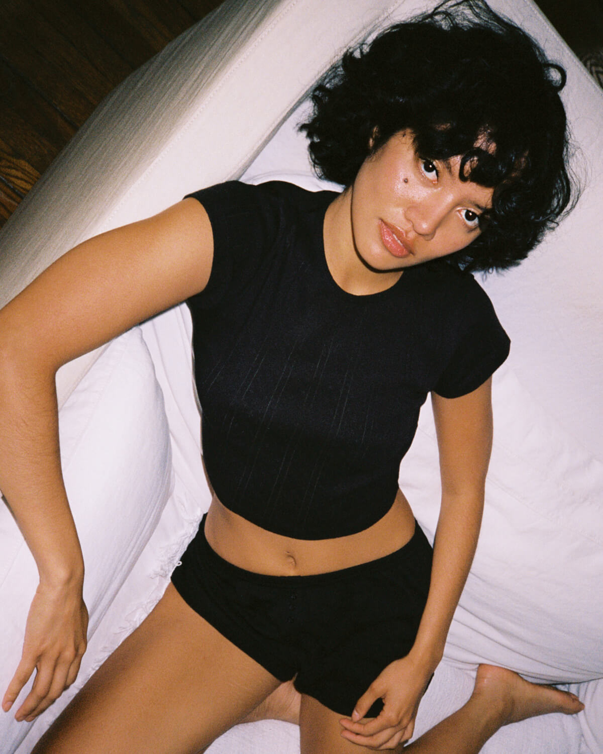 Person wearing a black crop top and shorts on a white background