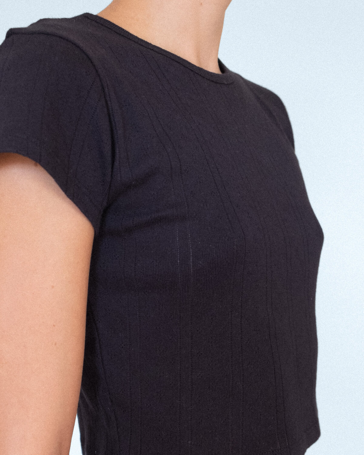 Black t-shirt worn by a person on a light blue background