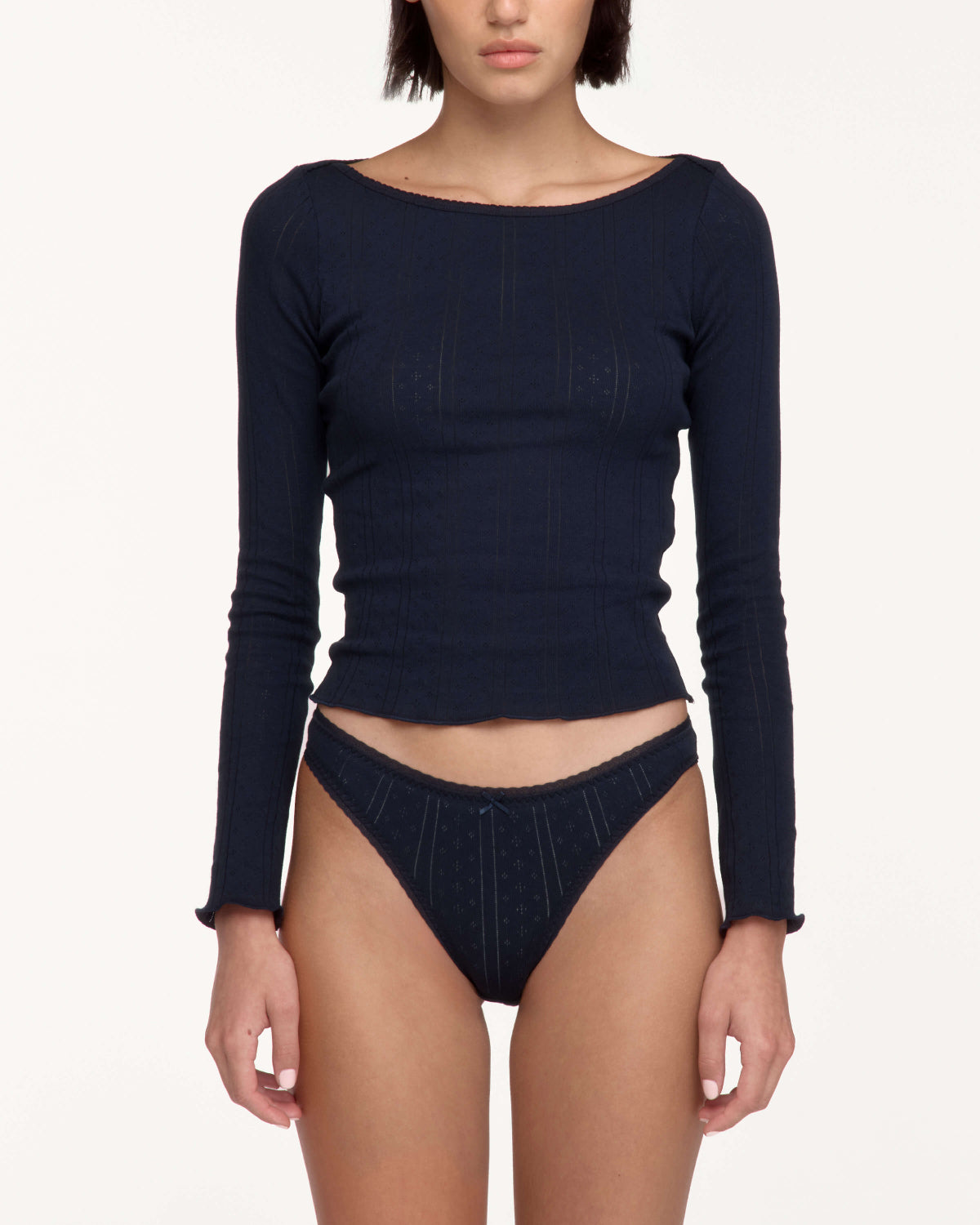 A model wearing a dark navy blue ribbed long-sleeve crop top and matching high-waisted underwear against a plain light background.