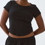 Person wearing a black crop top and pants against a plain background