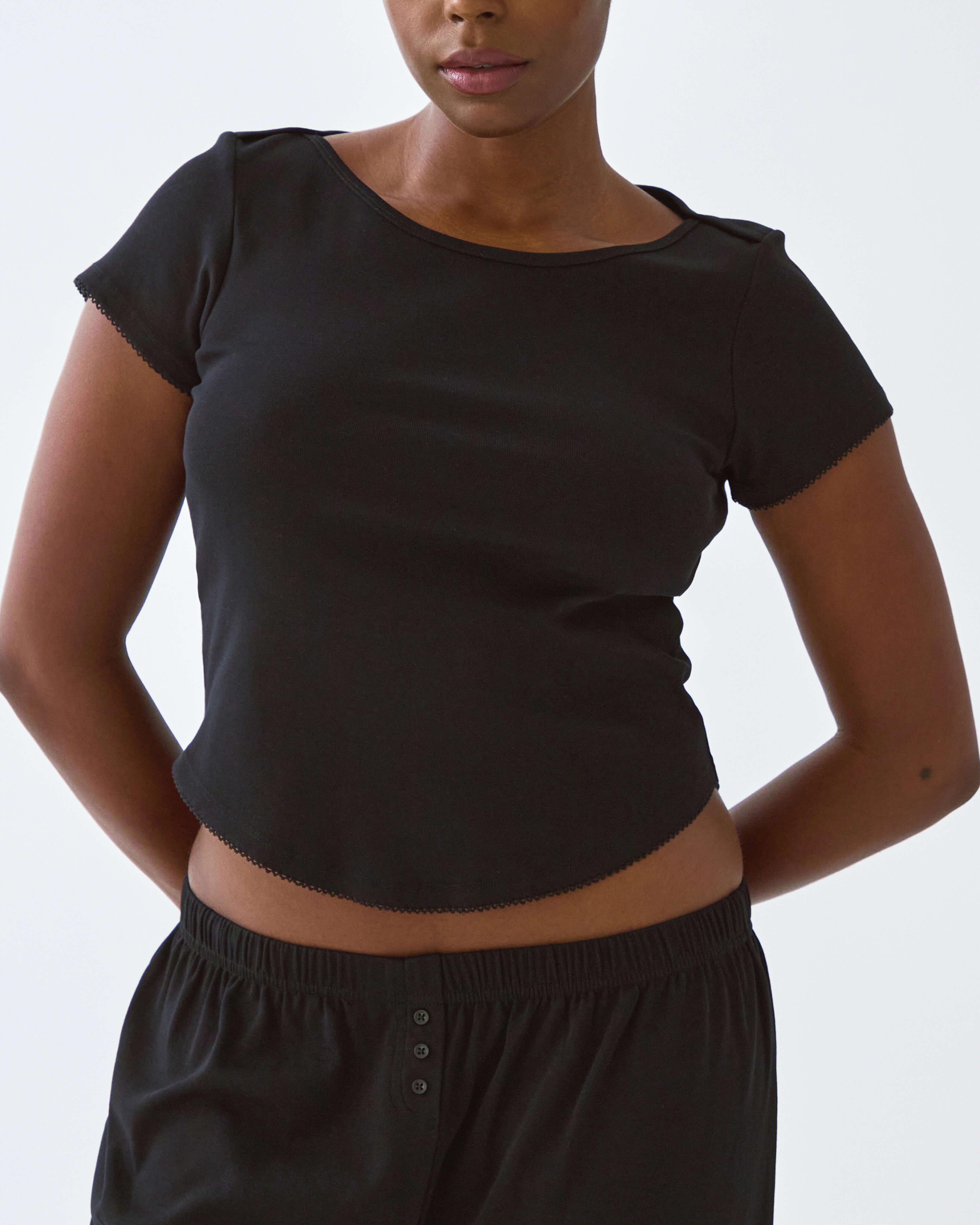 Person wearing a black crop top and pants against a plain background