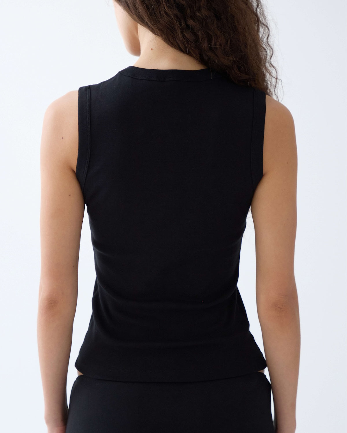 Person wearing a black sleeveless top on a white background