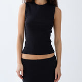 Woman wearing a black sleeveless top and a black skirt on a white background