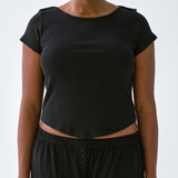 Person wearing a black crop top and black pants on a white background
