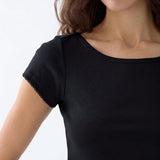 Close-up of a woman wearing a black short-sleeve top with a scoop neckline and delicate scalloped trim along the sleeve edge, against a plain light background.