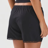 Black lace-trimmed shorts worn by a person on a white background