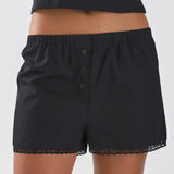 Black shorts with lace trim worn by a person on a white background
