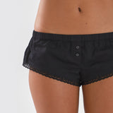Black lace-trimmed shorts worn by a person on a white background