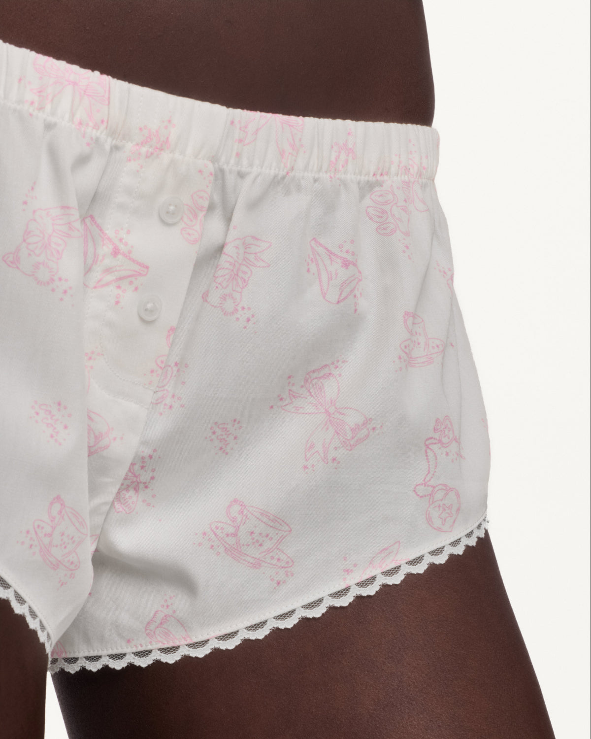 Close up of woman wearing white shorts with a pink pattern and lace trim. 