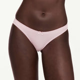 A close-up of a model wearing a light pink lace-trimmed underwear with a small bow at the center front, set against a plain white background.