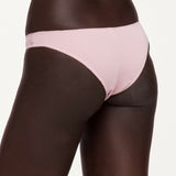 A close-up of a model wearing light pink underwear against a plain light background.