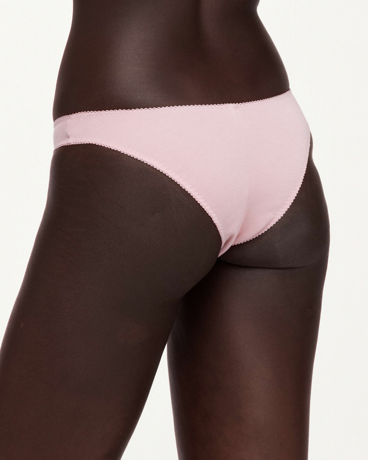A close-up of a model wearing light pink underwear against a plain light background.