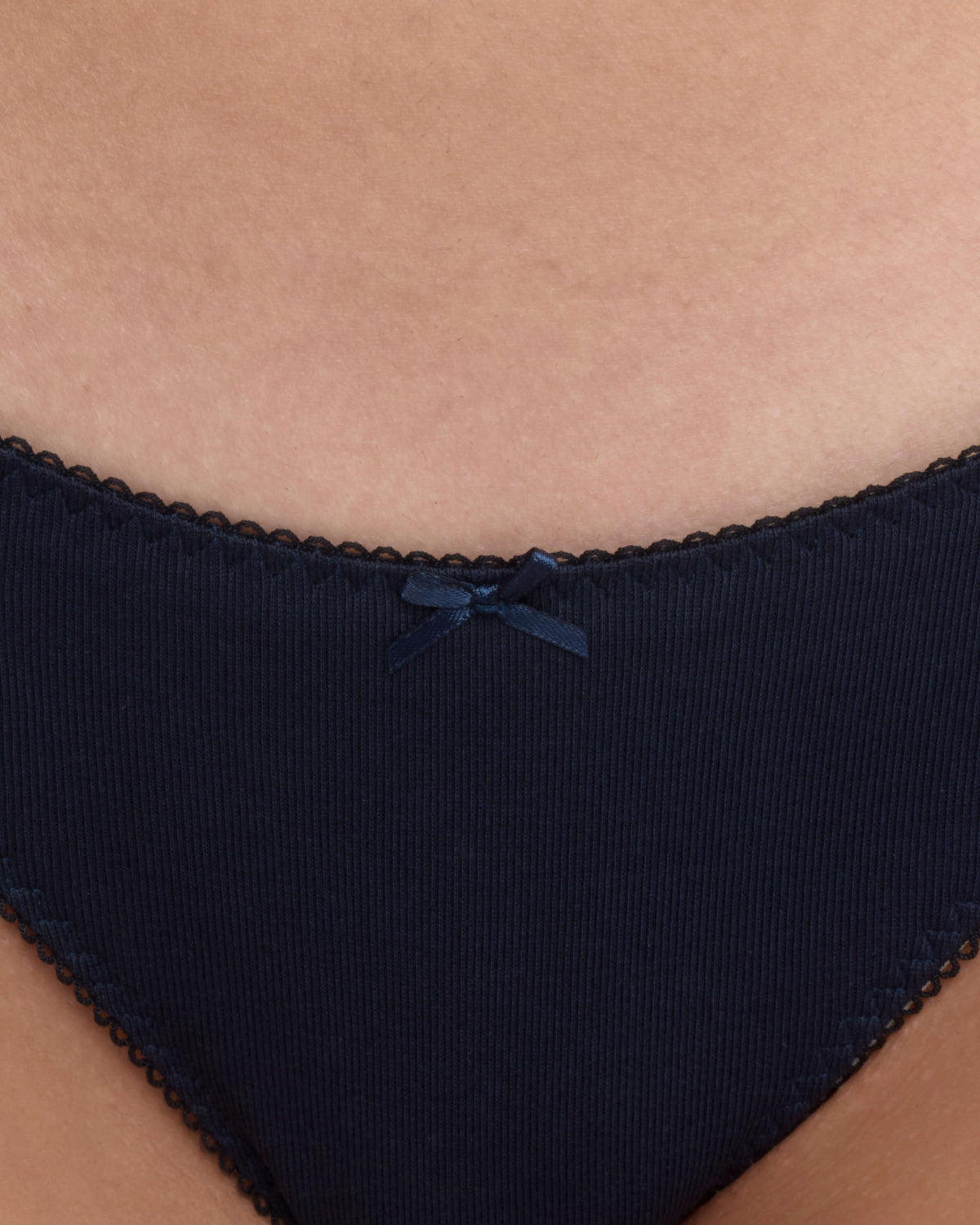 Close-up of a person wearing dark navy underwear with a small matching bow at the center front.