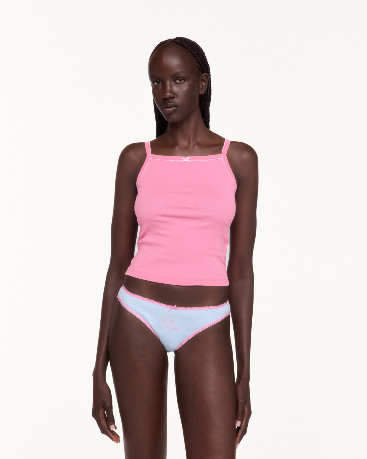 Woman wearing a pink tank top and white underwear with pink lace trim. 