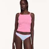 Woman wearing a pink tank top and white underwear with pink lace trim. 