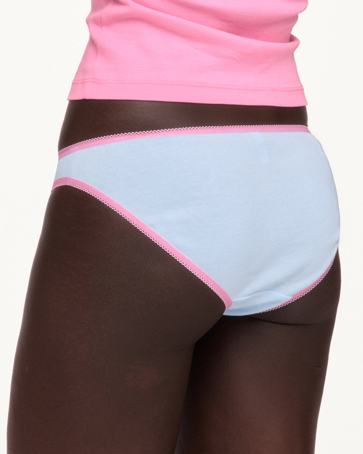 Woman wearing blue underwear with pink lace trim from the back. 