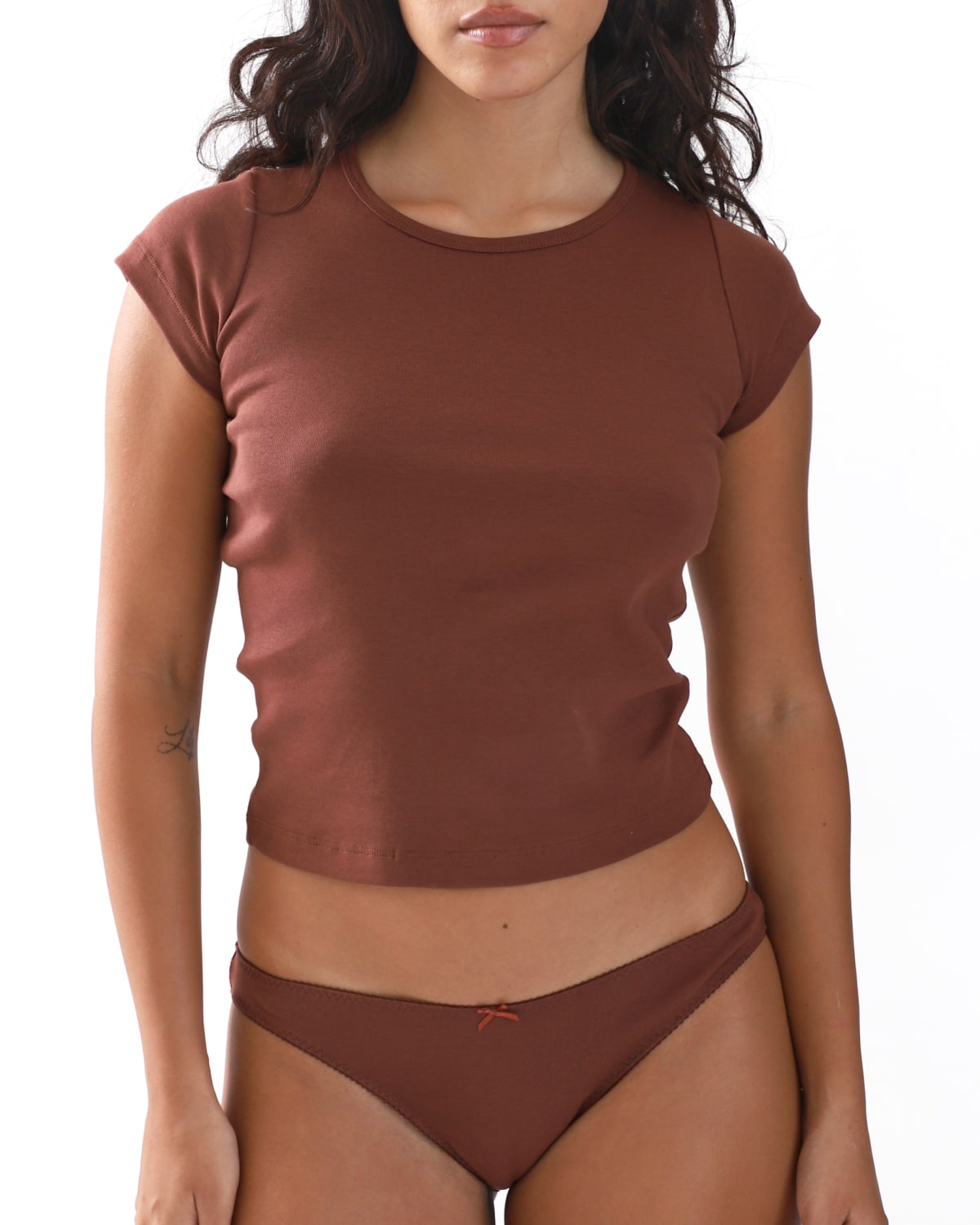 Woman wearing a brown cap-sleeve top and underwear set on a white background