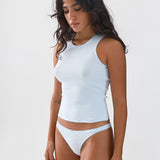 Woman wearing a light blue sleeveless top and briefs on a white background