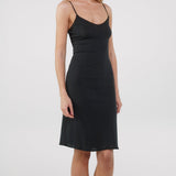 Black slip dress worn by a model on a white background
