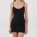 Black slip dress worn by a model on a white background