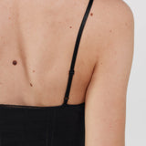 Black cami dress worn by a person on a plain background