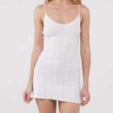 Woman wearing a white pointelle dress against a plain background