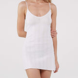 Woman wearing a white ribbed slip dress on a plain background