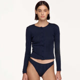 A model wearing a dark navy blue long-sleeve button-front cardigan and matching ribbed underwear, photographed against a clean off-white studio background.