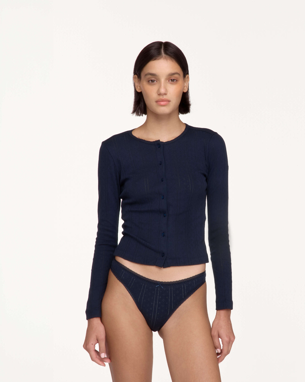 A model wearing a dark navy blue long-sleeve button-front cardigan and matching ribbed underwear, photographed against a clean off-white studio background.