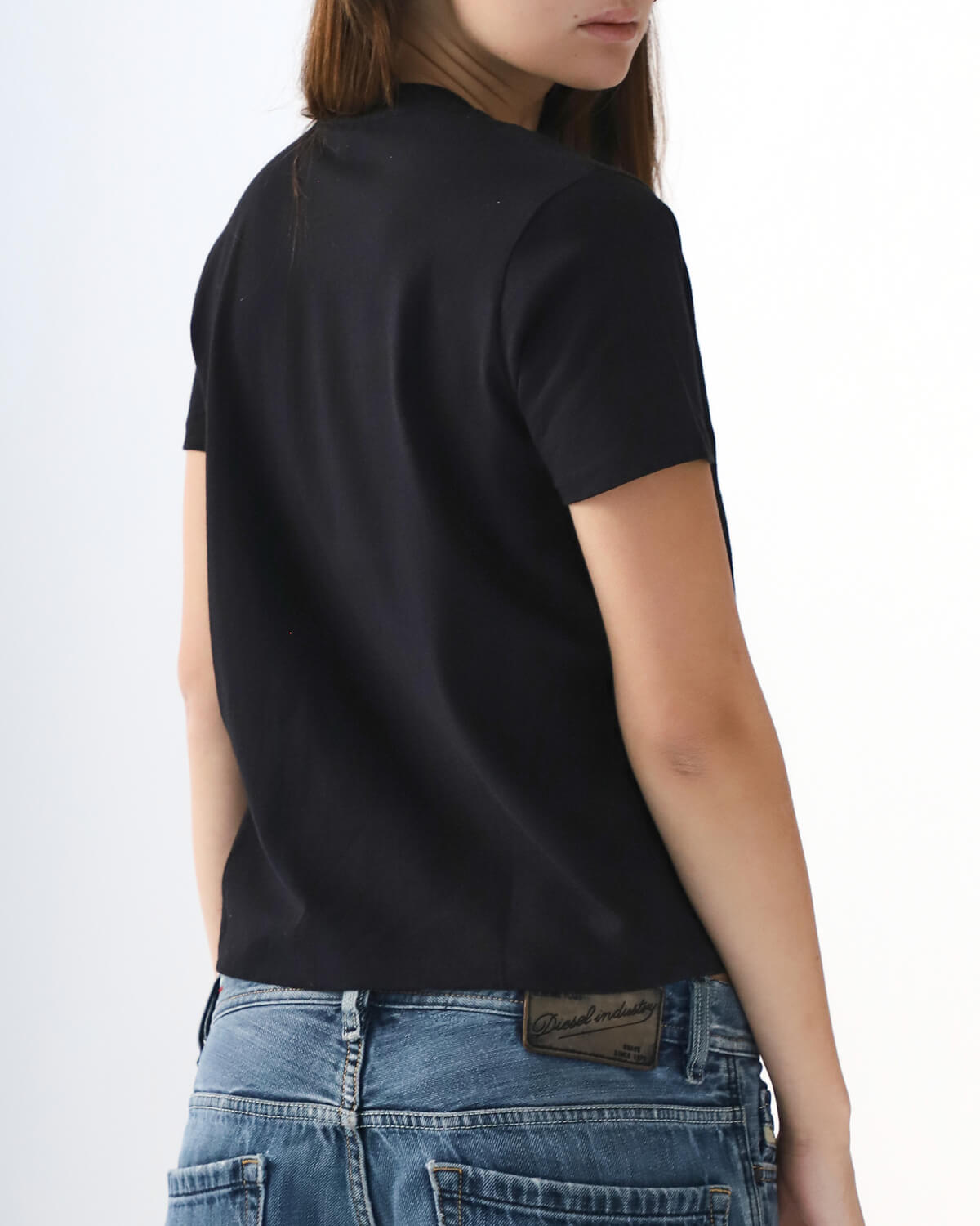 Person wearing a black t-shirt and blue jeans on a white background